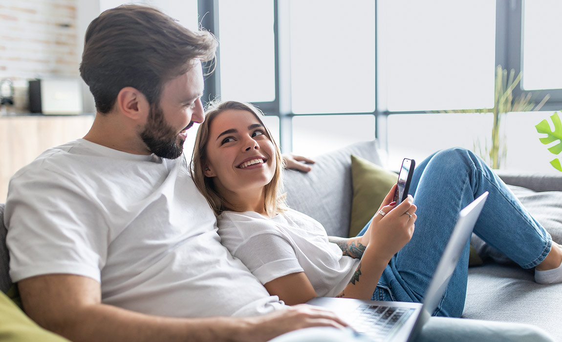 Young couple relaxing on a couch at home using a tablet